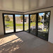 Spacious corner interior of Estholz Garden House WILLIAM featuring full-height glass doors allowing ample natural light and outdoor visibility.