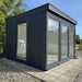 Stylish Estholz OLIVER garden building with full-height glass panels, dark timber cladding, and a compact footprint—ideal for use as a home office, studio, or outdoor retreat.