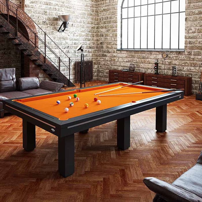 Etrusco Casino pool table with bold orange cloth and black frame, showcased in a rustic loft with parquet wood flooring and stone walls.