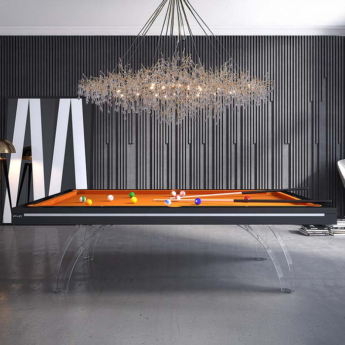 Etrusco P40 luxury pool table with clear acrylic legs, black frame and orange cloth, standing against textured dark wall panels beneath a sculptural designer chandelier.