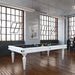 White Etrusco Smile pool table with black cloth, styled in an industrial-inspired interior with tall windows and wooden flooring.