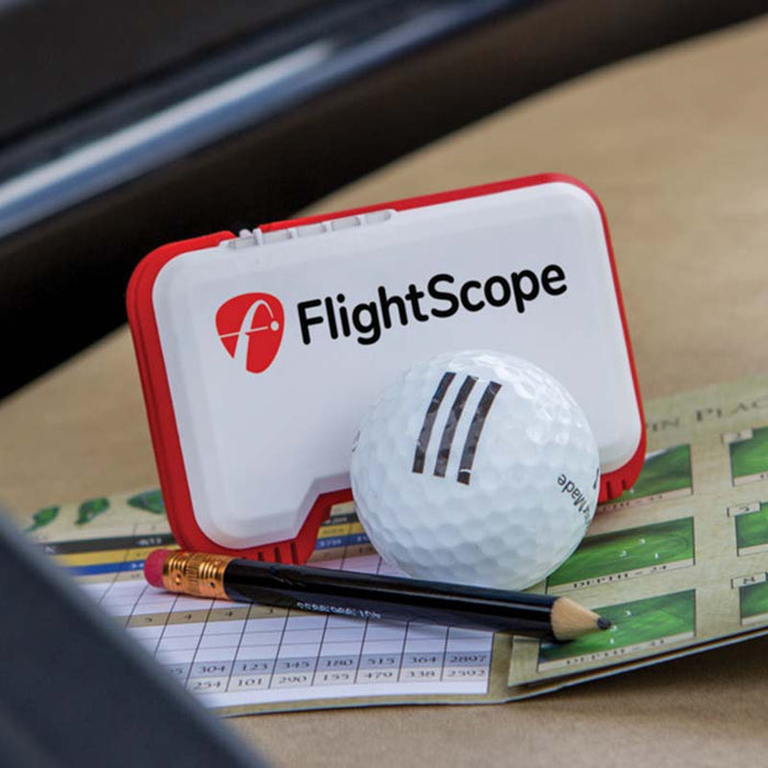 FlightScope Mevo on a scorecard next to a golf ball and pencil.