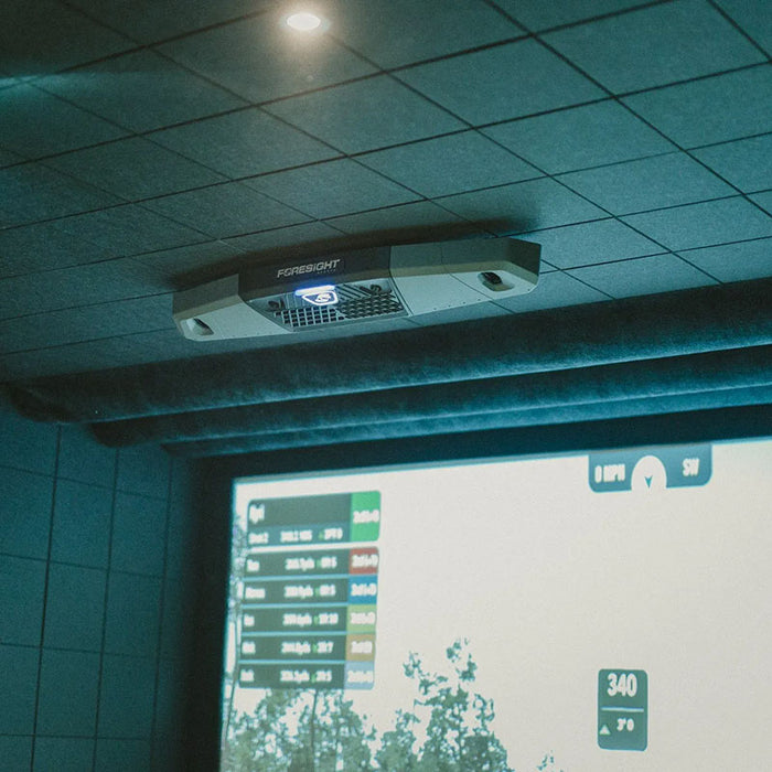 Foresight Falcon launch monitor in action above a golf simulator screen, with high-resolution tracking and shot data displayed in real time.