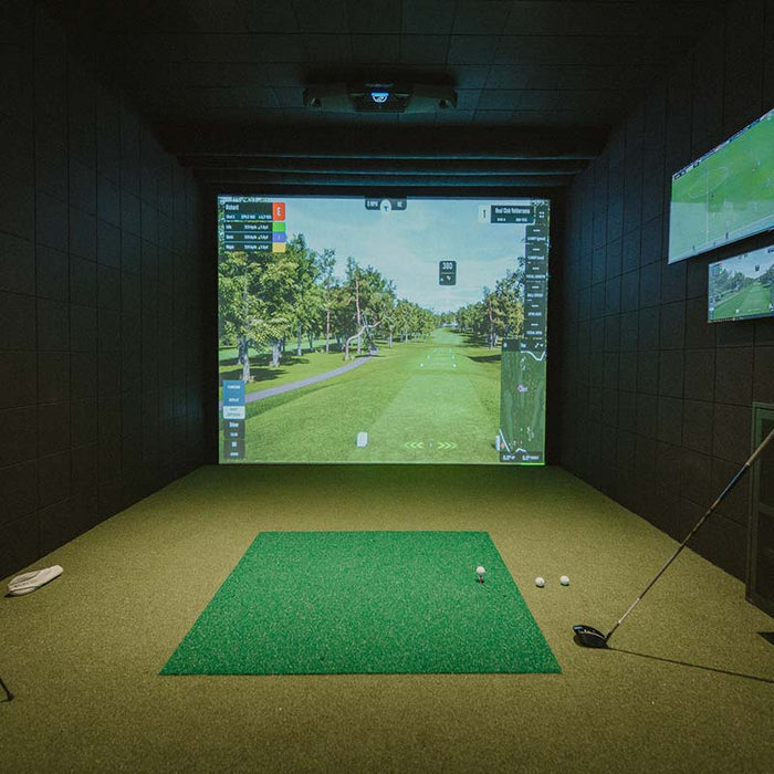 Cosy indoor golf simulator room with Foresight Falcon overhead launch monitor and immersive screen, set in a stylish loft with modern furnishings.