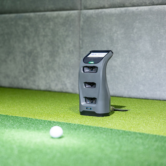 Indoor close-up of the Foresight GC3 Launch Monitor aimed toward a golf ball, ready for swing data analysis.