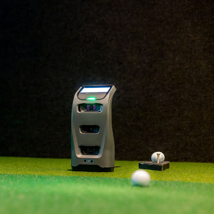 Foresight GC3 Launch Monitor in an indoor golf simulator setup, positioned near tee and golf balls for shot tracking.