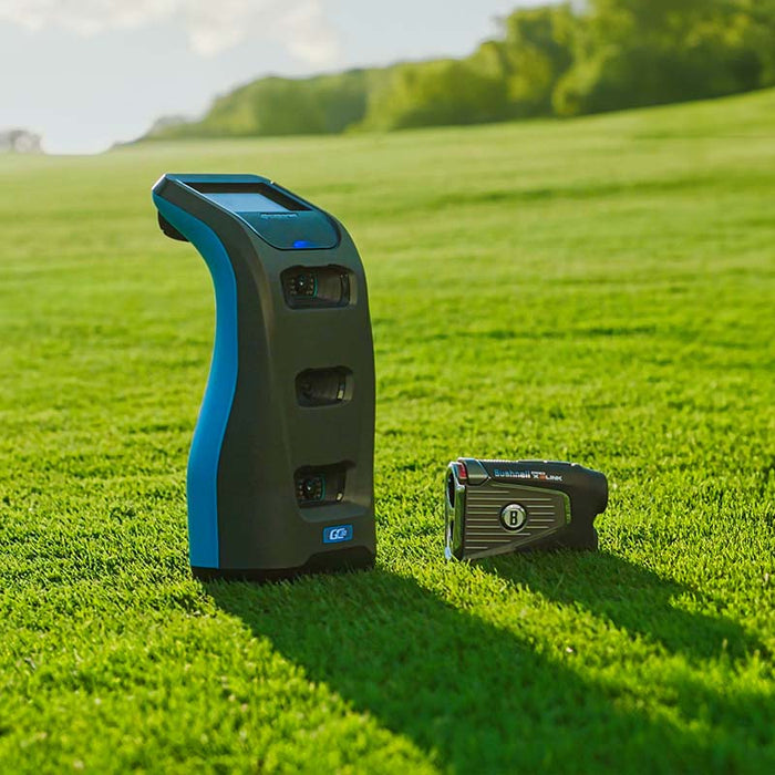 Foresight GC3S Launch Monitor on lush grass next to a rangefinder, demonstrating versatile golf technology on the course.