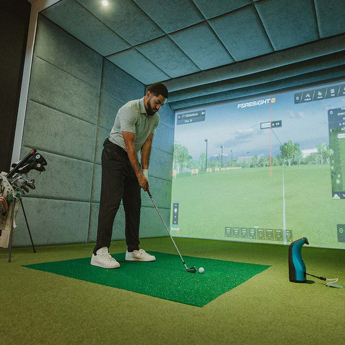 Golfer indoors using the Foresight GC3S Launch Monitor with a golf simulator, ideal for indoor swing practice and virtual play.