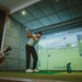 Golfer at top of backswing in indoor simulator using Foresight GC3S Launch Monitor to record full-swing data.