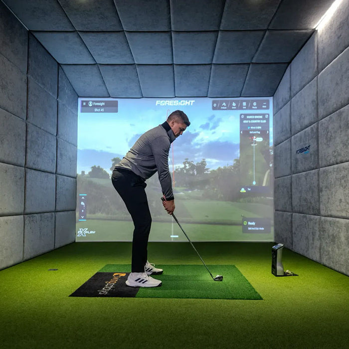 Golfer at address position in a golf simulator using the Foresight GCQuad for accurate shot tracking.