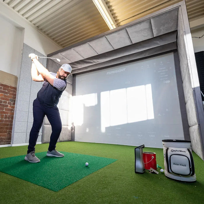 Golfer at the top of backswing in an indoor simulator using the Foresight GCQuad Launch Monitor.