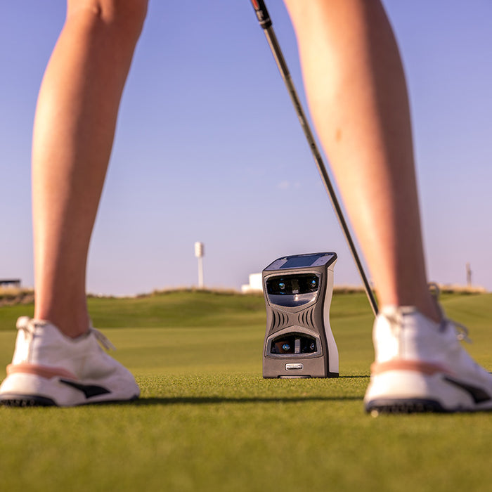 Golfer standing behind the Foresight QuadMAX golf launch monitor during an outdoor session on the course.