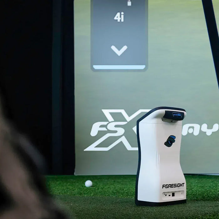 Indoor setup of the Foresight QuadMAX launch monitor beside a golf simulator screen, perfect for year-round practice.