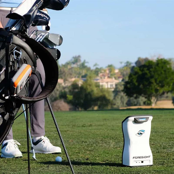 Foresight QuadMAX launch monitor on the fairway next to a golfer and their bag, ready for on-course swing data capture.