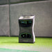 Foresight QuadMAX Launch Monitor positioned indoors on turf against a padded wall, screen displaying shot data.