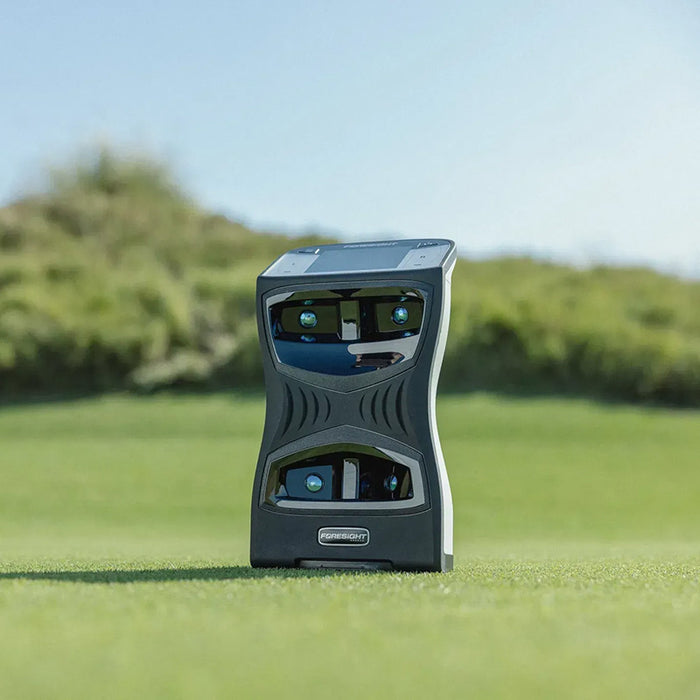 Foresight QuadMAX Launch Monitor on lush fairway with green foliage in the background under blue sky.