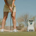 Golfer putting on green with Foresight QuadMAX Launch Monitor capturing stroke data under sunny conditions.