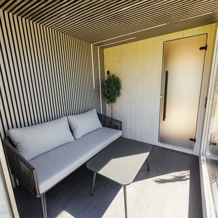 Cosy Geneva St. Moritz outdoor sauna terrace with sofa, frosted door, and full-height glass wall overlooking landscape.