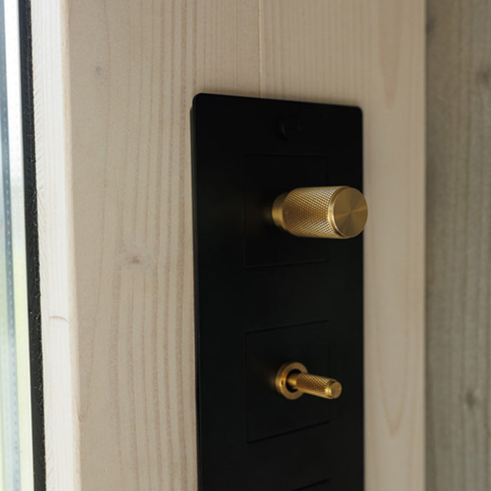 Zoomed-in view of elegant golden rotary dimmer and toggle switches inside Geneva St. Moritz outdoor sauna, mounted on natural wood.