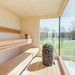 Bright wooden sauna interior with HUUM heater and copper accessories inside Geneva St. Moritz outdoor sauna, with floor-to-ceiling window.