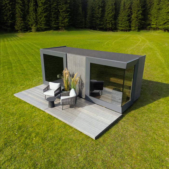 Modern Geneva St. Moritz outdoor sauna cabin with shower room, set in a scenic forest clearing, featuring sleek black-framed glass panels and stylish patio seating.