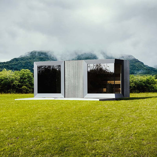Geneva St. Moritz outdoor sauna with shower room set against dramatic misty mountain backdrop, showcasing sleek mirrored glass panels and contemporary modular design in nature.
