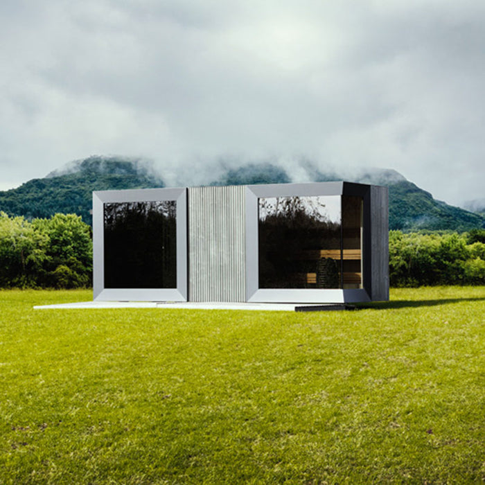 Geneva St. Moritz outdoor sauna with shower room set against dramatic misty mountain backdrop, showcasing sleek mirrored glass panels and contemporary modular design in nature.