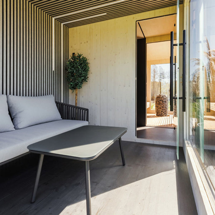 Modern Geneva St. Moritz sauna lounge with glass door open, showing interior heater and natural wood finishes.