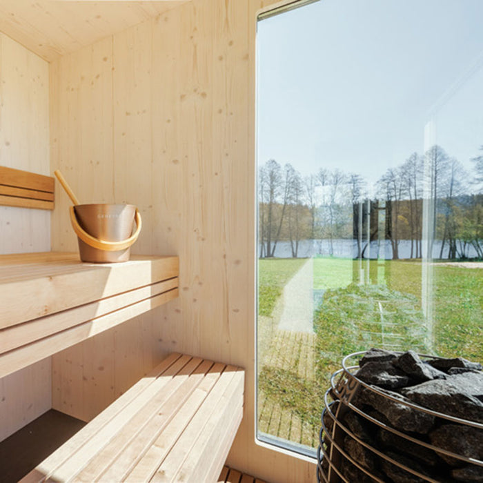 Minimalist sauna interior in Geneva St. Moritz unit with Geneva copper bucket and ladle, wide wooden bench seating and large window.
