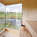 Interior view of the Zermatt outdoor sauna with natural wood finish and full-height glass windows overlooking a scenic pond and greenery.