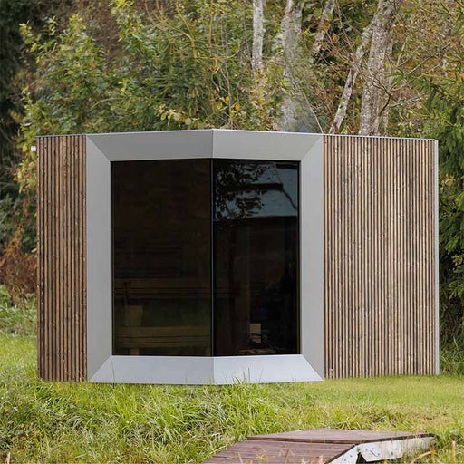 Modern Zermatt outdoor sauna cabin with changing room, featuring sleek timber cladding and panoramic front glass, set in a tranquil forest clearing.