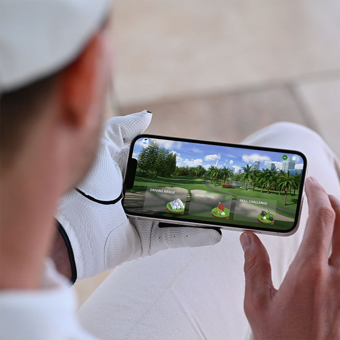 A golfer using the Golfjoy GDS Plus Launch Monitor app on a mobile phone, demonstrating the ease of accessing real-time data and practice sessions.