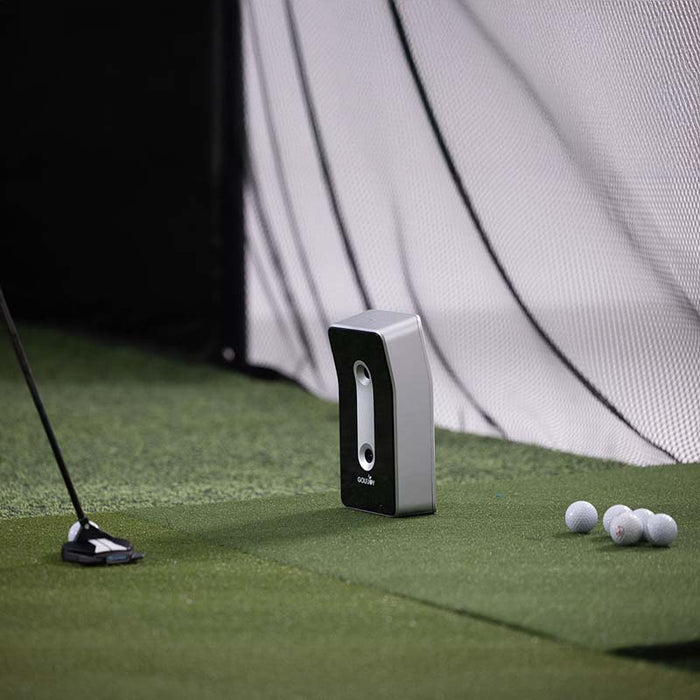 Close-up view of the Golfjoy GDS Plus launch monitor on a green mat with golf balls nearby.