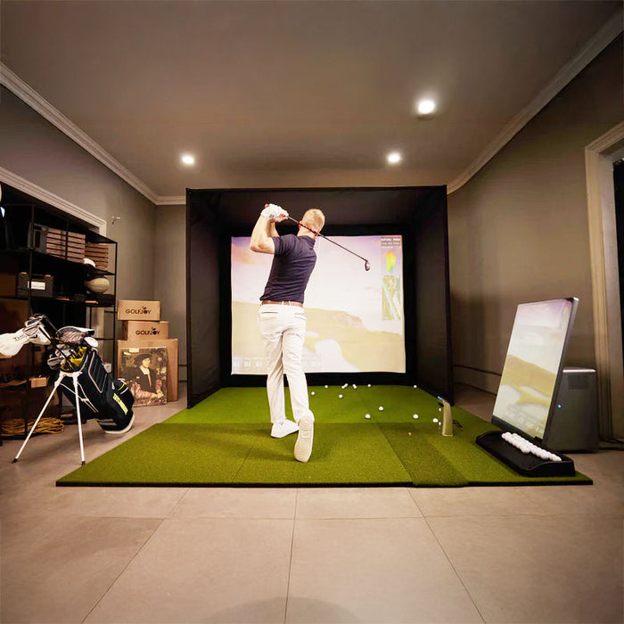 Side angle of the Golfjoy Personal Golf Simulator, showcasing the monitor and accessories within a realistic golf training setup.