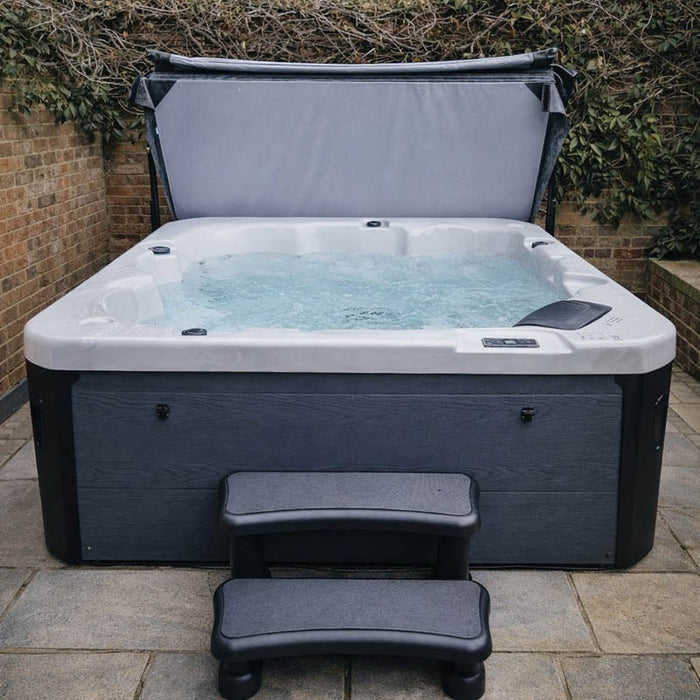 Front-on view of the H2O Azure 5-Person Hot Tub with cover lifter open and entry steps, dark grey woodgrain cabinet and white acrylic shell