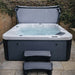 Front-on view of the H2O Azure 5-Person Hot Tub with cover lifter open and entry steps, dark grey woodgrain cabinet and white acrylic shell