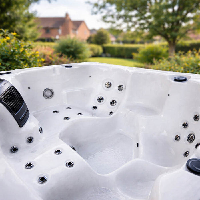 Close-up interior view of the H2O Azure 5-Person Hot Tub showing jet placement, built-in speaker, and white acrylic shell with garden backdrop