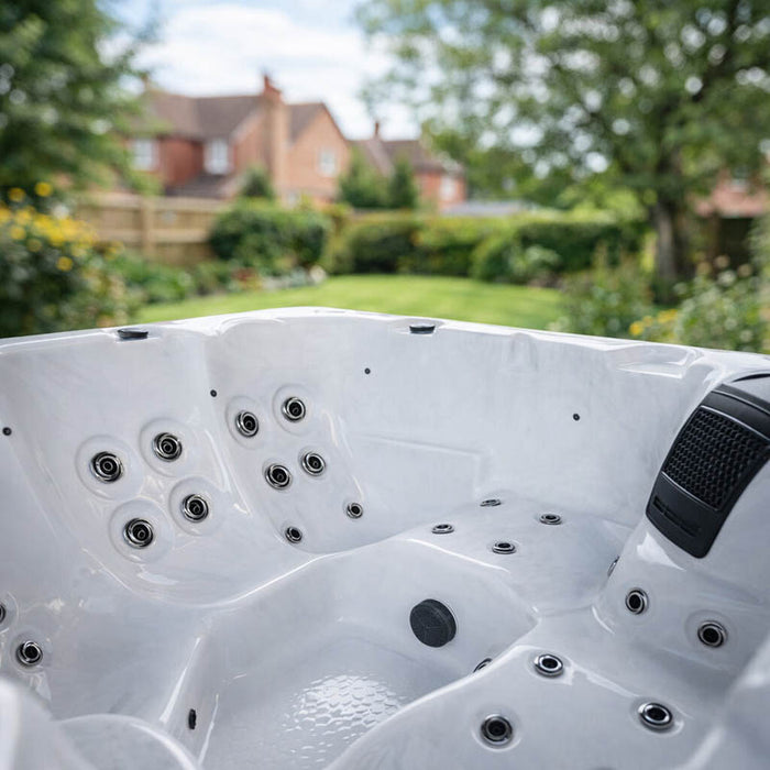 Angled interior detail of the H2O Azure 5-Person Hot Tub showing hydrotherapy jets across white acrylic seating and built-in speaker unit
