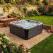 H2O Coral 5-Person Hot Tub in a UK garden with outdoor dining and BBQ area in the background, jets running