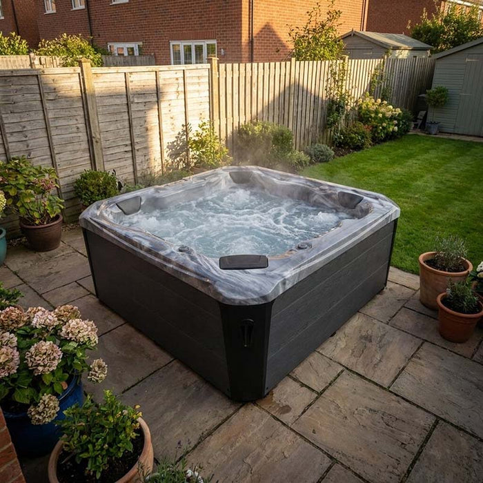 H2O Coral 5-Person Hot Tub in a UK garden at dusk surrounded by hydrangeas and potted plants, steam rising from the water