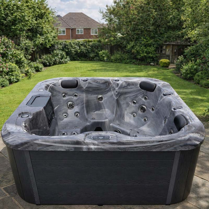 H2O Retreat Pro 5-Person Hot Tub with dark grey marbled shell and charcoal cabinet installed on a stone patio in a UK garden