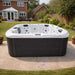 H2O Retreat Pro 5-Person Hot Tub with white shell and dark cabinet positioned on a garden lawn beside a conservatory