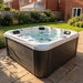 H2O Retreat Pro 5-Person Hot Tub with white shell and dark cabinet on a stone patio in a UK garden with conservatory in the background
