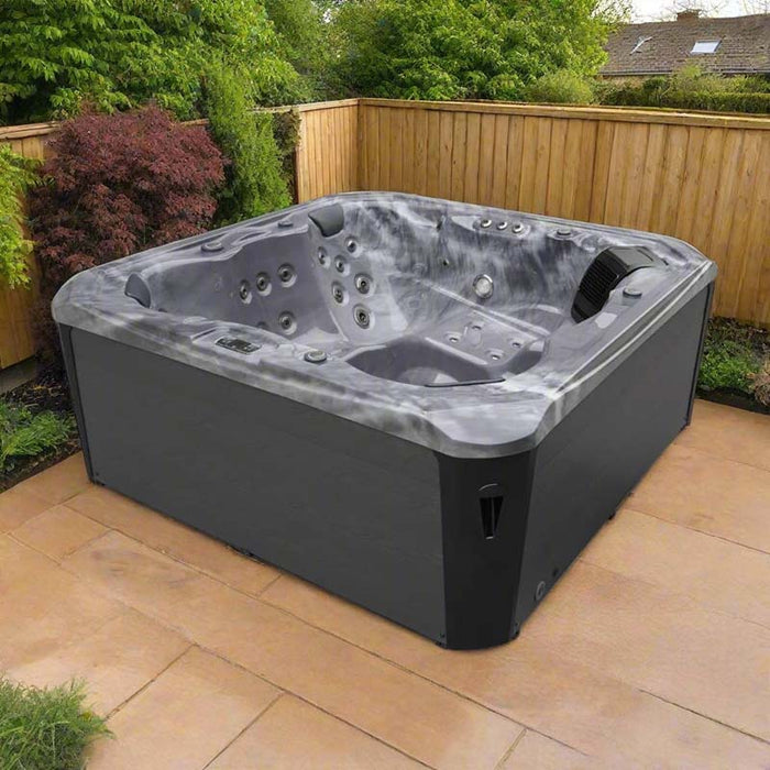 H2O Vortex 6-Person Hot Tub with grey marbled shell and charcoal cabinet shown from an angled view on a sandstone patio with timber fence backdrop