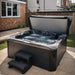 H2O Vortex 6-Person Hot Tub with grey shell and dark charcoal cabinet, cover open showing active jets, installed on a paved patio in a UK suburban garden with entry steps