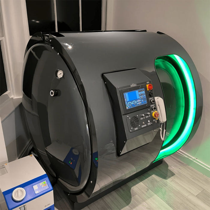 Side angle view of Henshaw Duoplace Chamber illuminated with green LED, highlighting its modern curved design and integrated monitoring system.