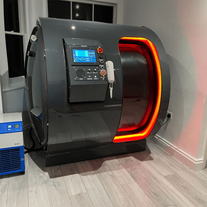 Henshaw Duoplace Hyperbaric Oxygen Chamber with striking red LED illumination, positioned in a private clinical room with advanced external oxygen system.