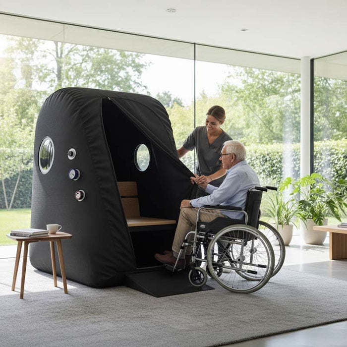 Carer assisting elderly man in a wheelchair into the Henshaw Easy Access Hyperbaric Oxygen Chamber for safe and inclusive wellness treatment.
