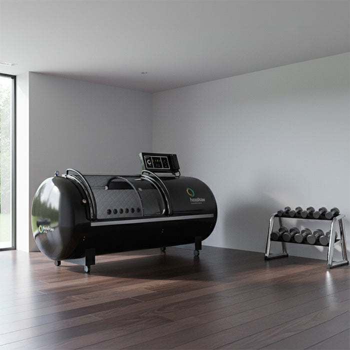 Gym recovery zone with Henshaw Pro Hyperbaric Oxygen Chamber positioned beside weights and wellness bench, ideal for post-workout oxygen therapy.