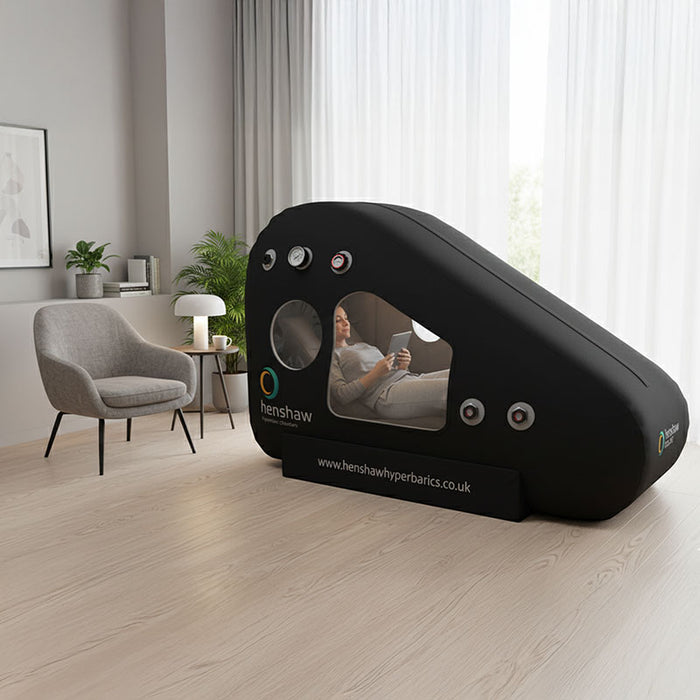 Woman relaxing inside the Henshaw Recline Hyperbaric Chamber while reading, showcasing comfortable and effective oxygen therapy.